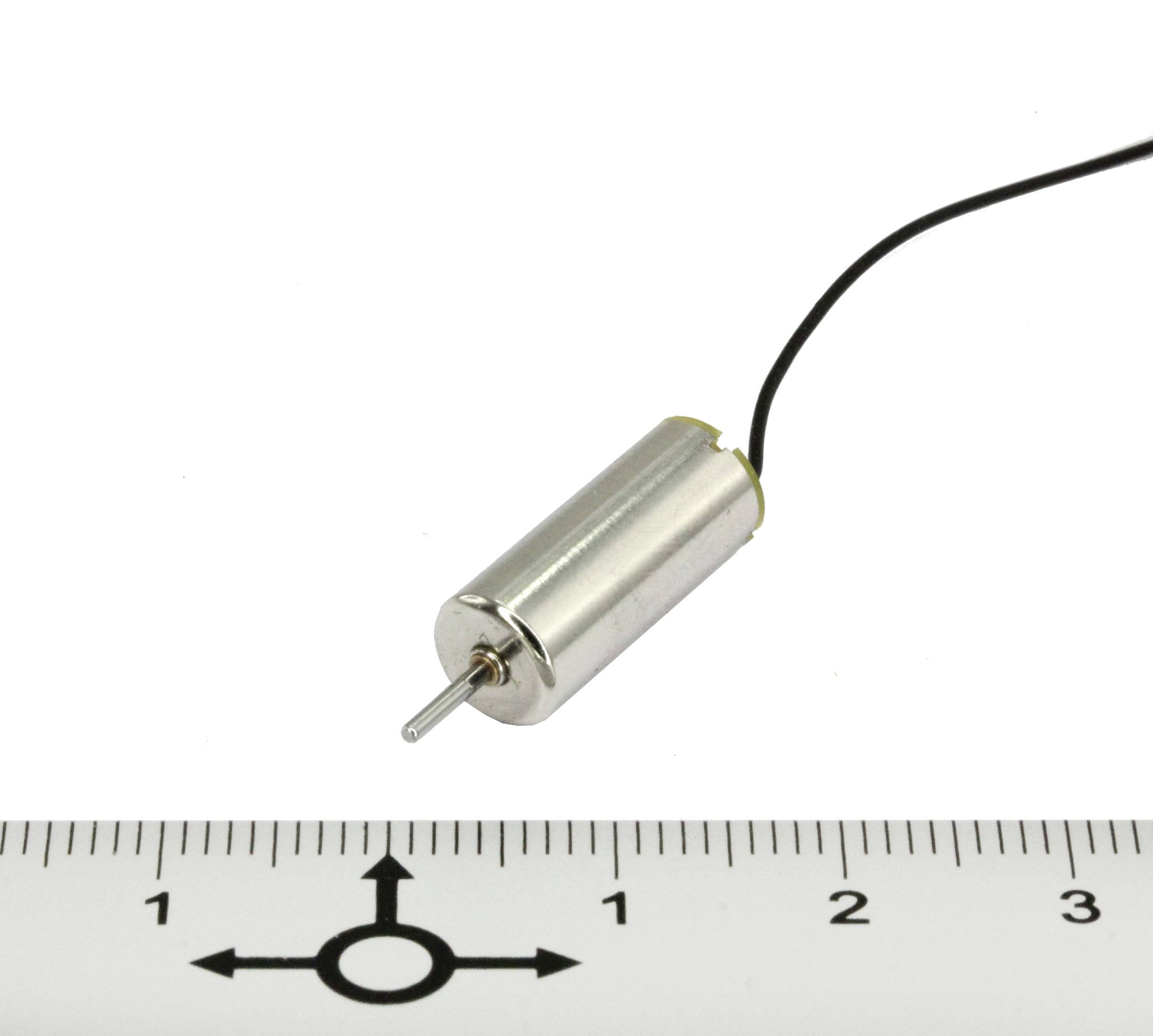 Malý elektromotor s kabelem je zobrazen vedle pravítka se stupnicí v centimetrech.