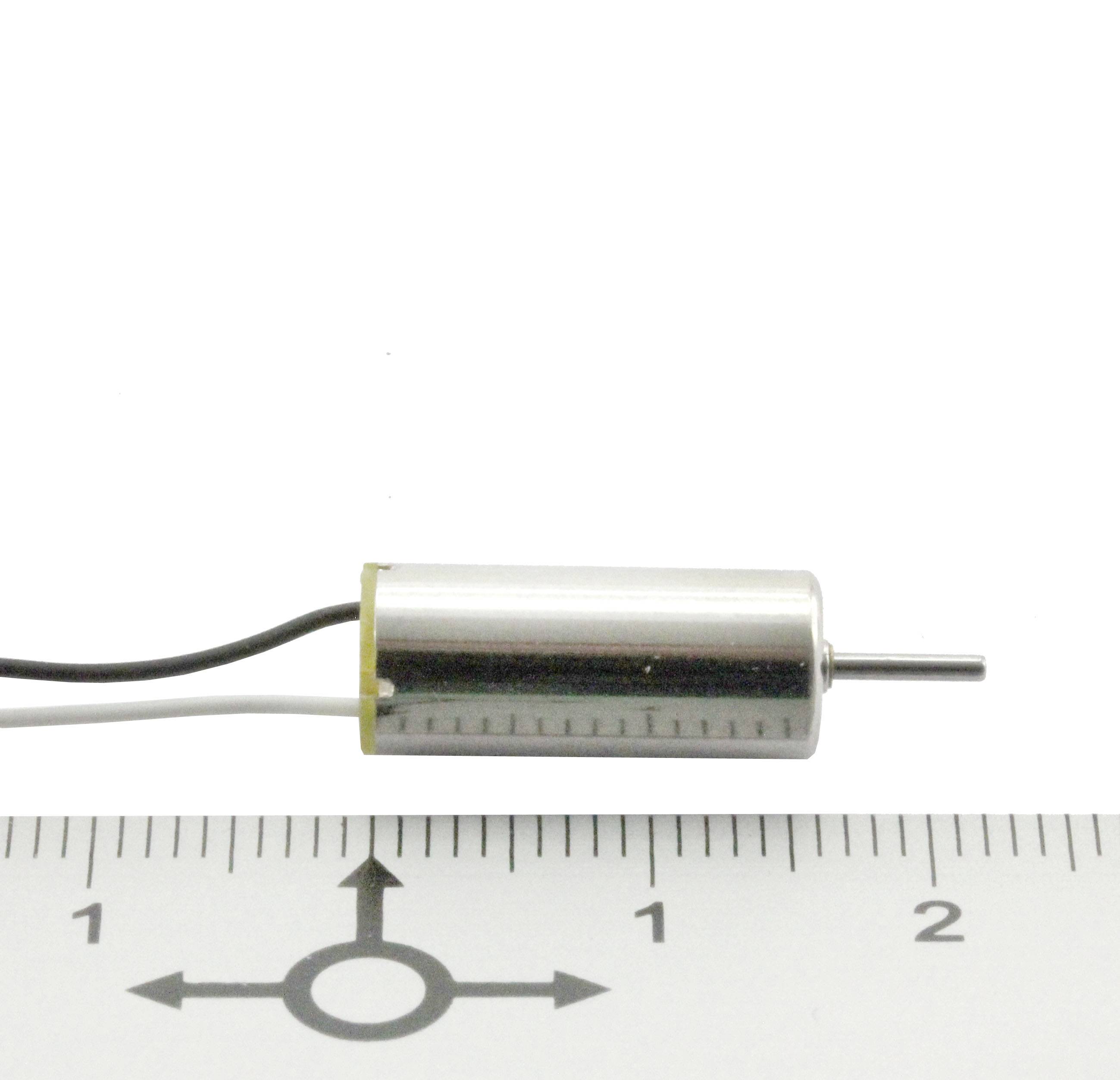 Malý válcový elektromotor vedle pravítka, ukazující délku přibližně 2,3 cm. Kabel vede od motoru.