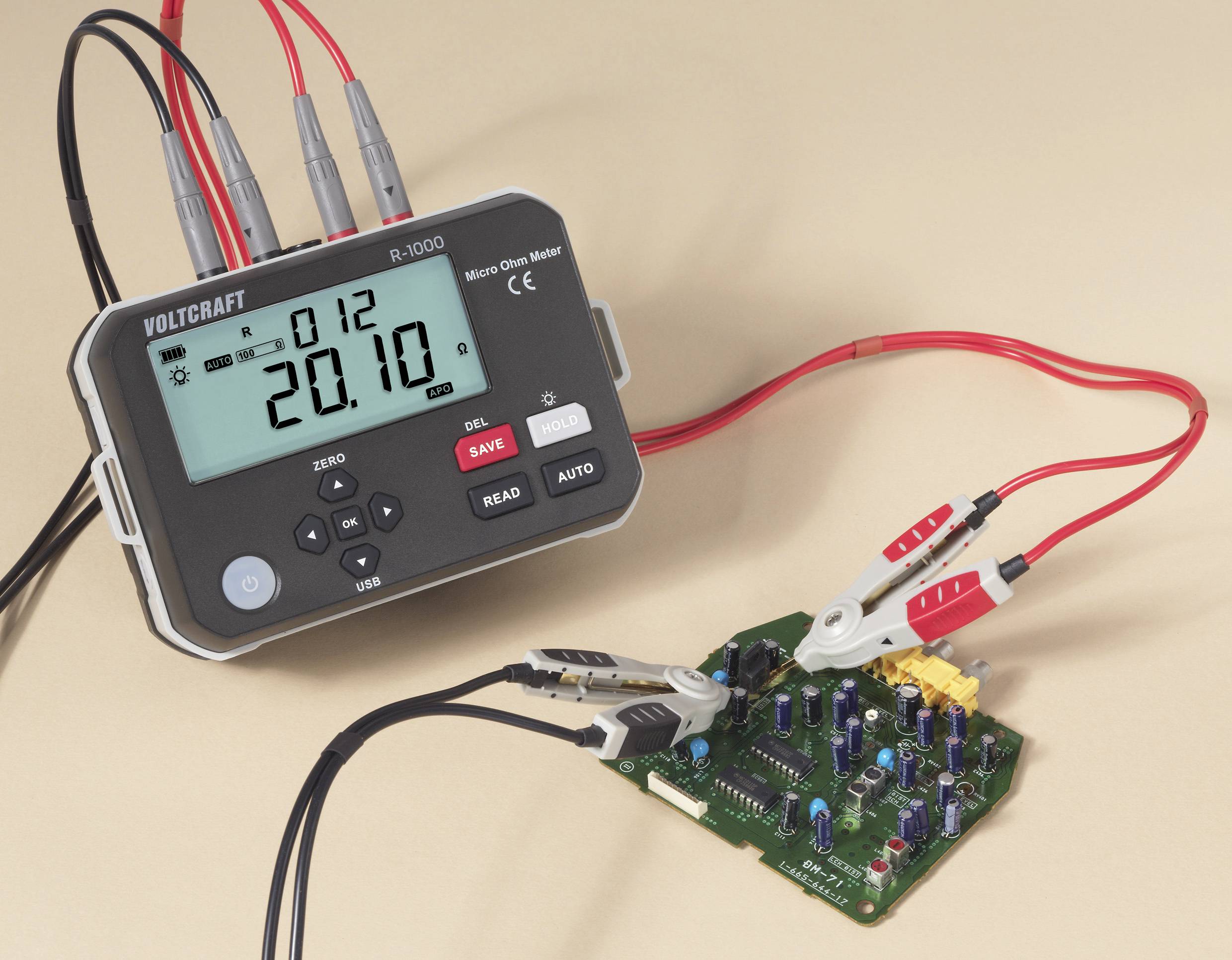 Digitální multimetr s připojenými vodiči zobrazuje hodnotu '20,10' a je připojen k elektronické desce plošných spojů s různými komponenty.