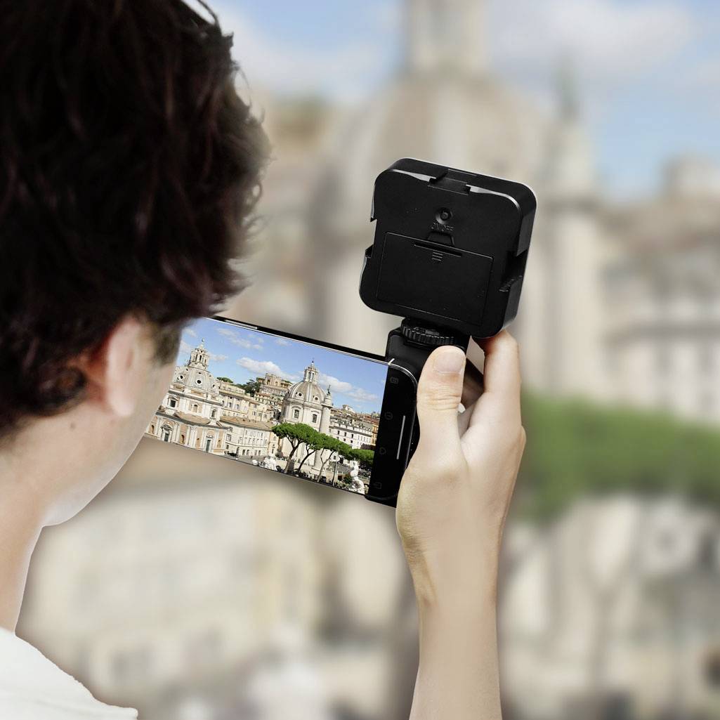 Osoba fotí budovu s kopulí pomocí svého smartphonu. Zaměření je na displeji mobilního telefonu a fotografovaném motivu.