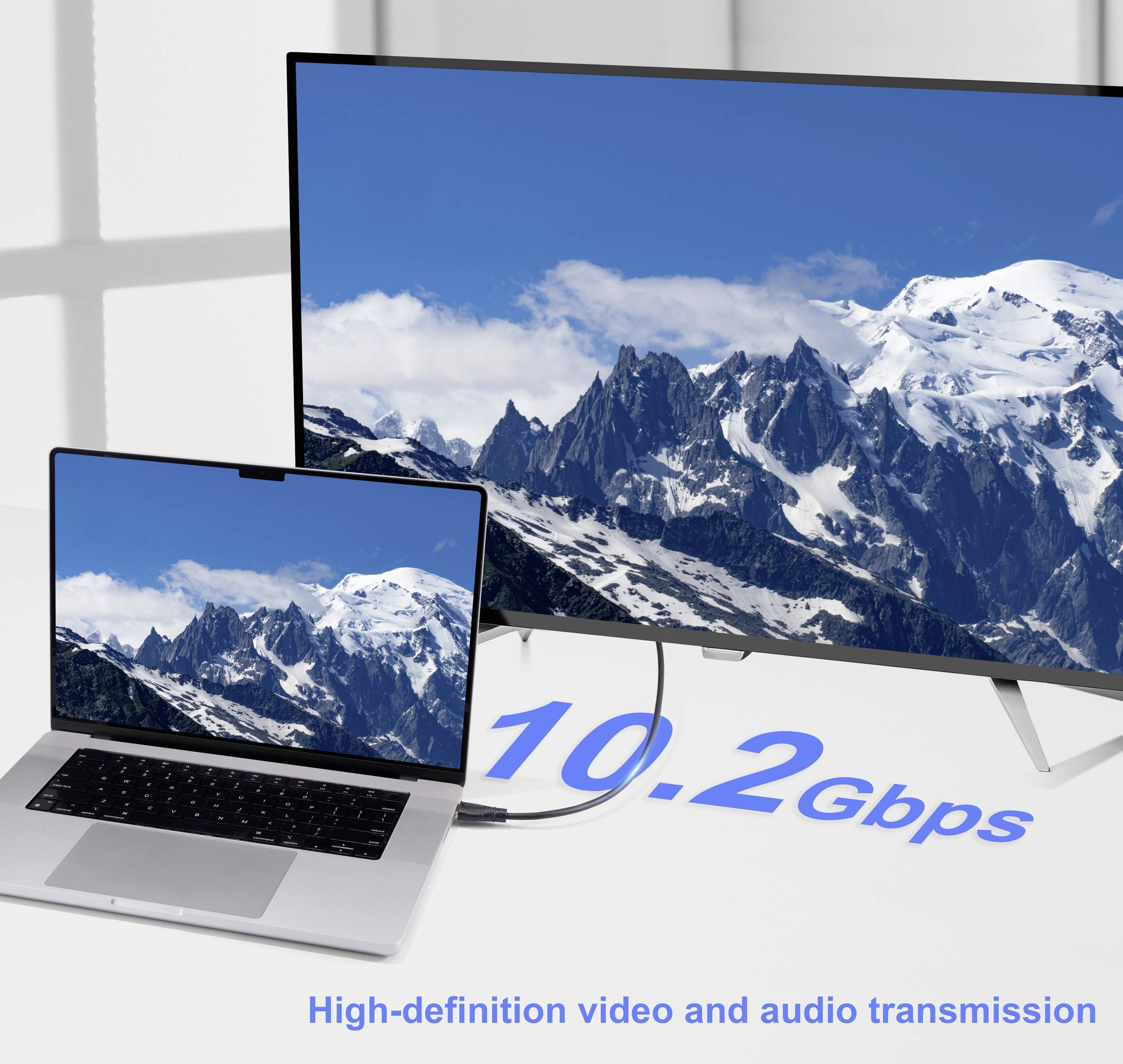 Notebook je připojen k velkému monitoru zobrazujícímu zasněžené hory. Text hlásí '10.2 Gbps'. Sestava zdůrazňuje rychlý přenos dat.