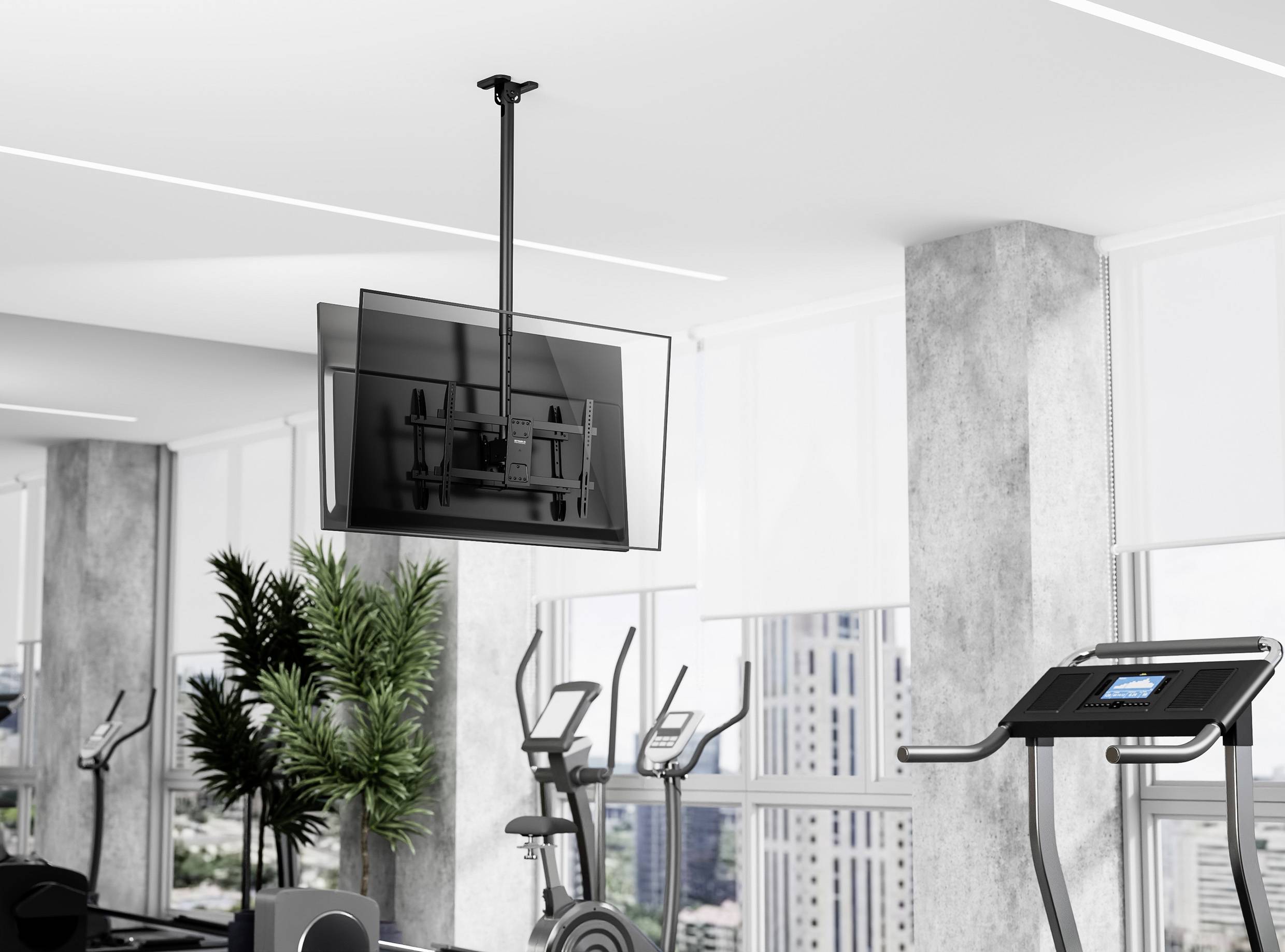 Moderní posilovna s fitness vybavením, včetně běžeckého pásu a stacionárních kol. Na stěně je zavěšený televizor a v pozadí je výhled na město.