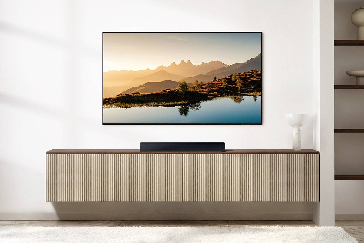 Moderní, minimalistický prostor s plochou obrazovkou televizoru zobrazující malebnou krajinu s horami a jezerem.
