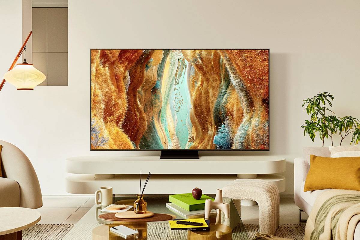 Moderní obývací pokoj s plochým televizorem, který zobrazuje abstraktní, barevné umělecké dílo. V místnosti jsou elegantní nábytek a rostliny.