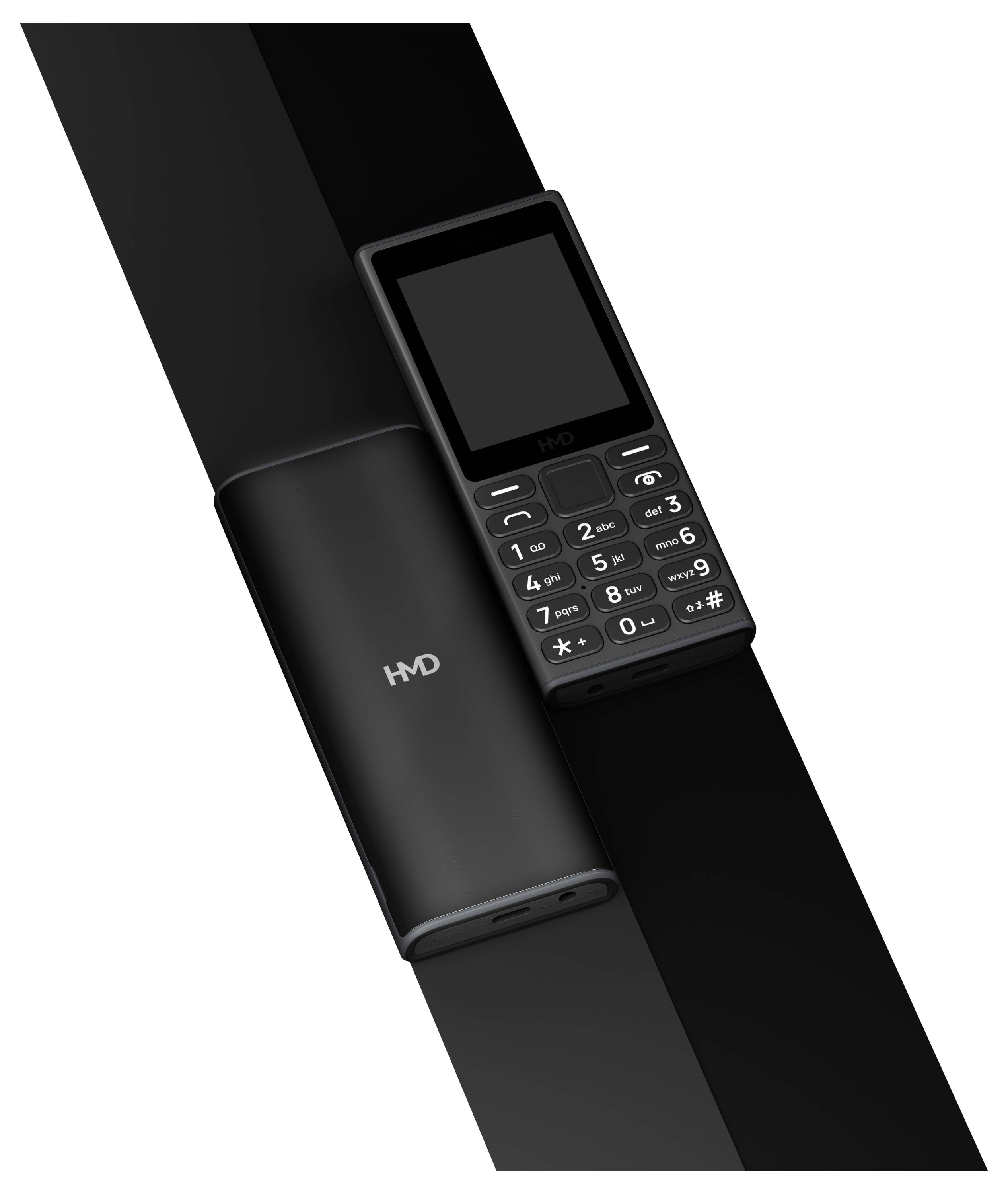 Jednoduchý mobilní telefon s tlačítky vedle válcovité nabíječky, oba v černé barvě a s podobným designem.