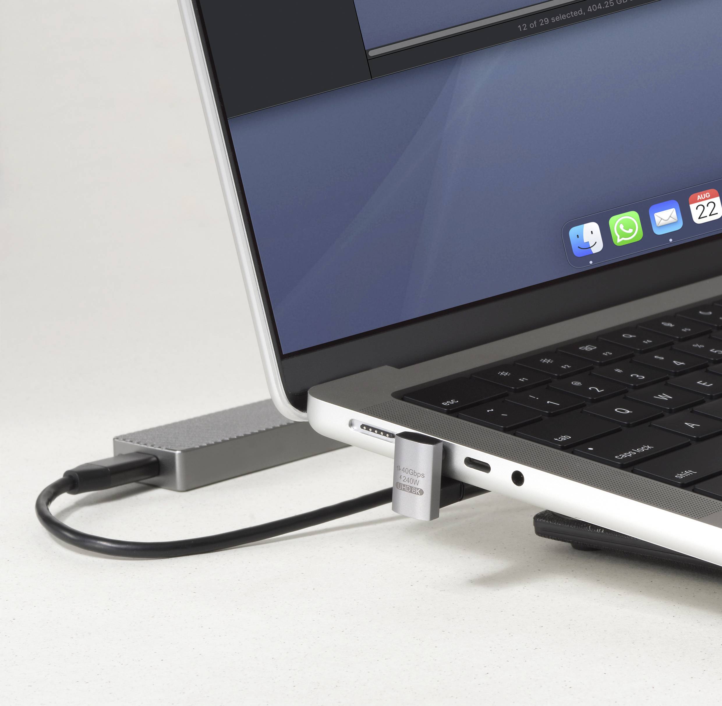 Detailní pohled na boční stranu laptopového počítače, zobrazující různé porty a zasunutý USB disk. Na rozostřené obrazovce jsou viditelné ikony několika aplikací.