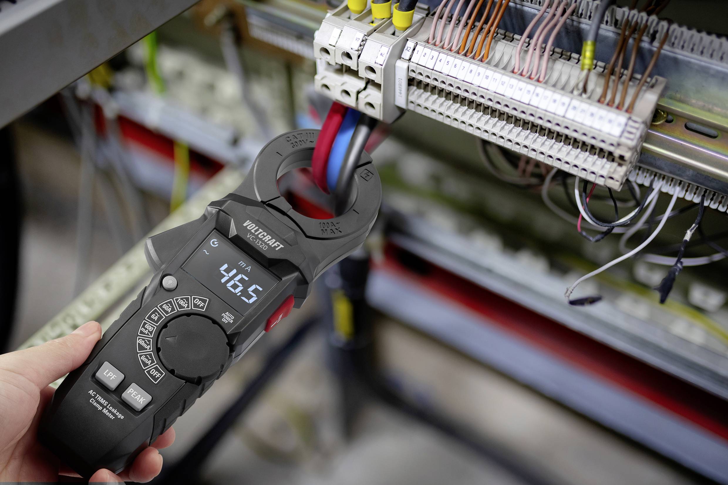 Osoba používá digitální kleštové ampérmetricky měřit elektrický proud v obvodu s více vodiči a displej ukazuje hodnotu 46,5.