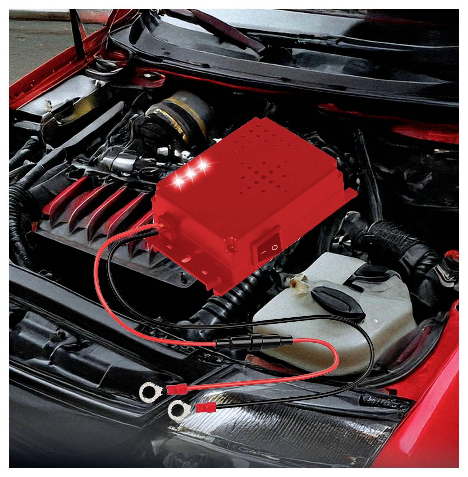 Automotor s červeným elektronickým zařízením připojeným k baterii, který se pravděpodobně používá k diagnostice nebo řízení napájení.