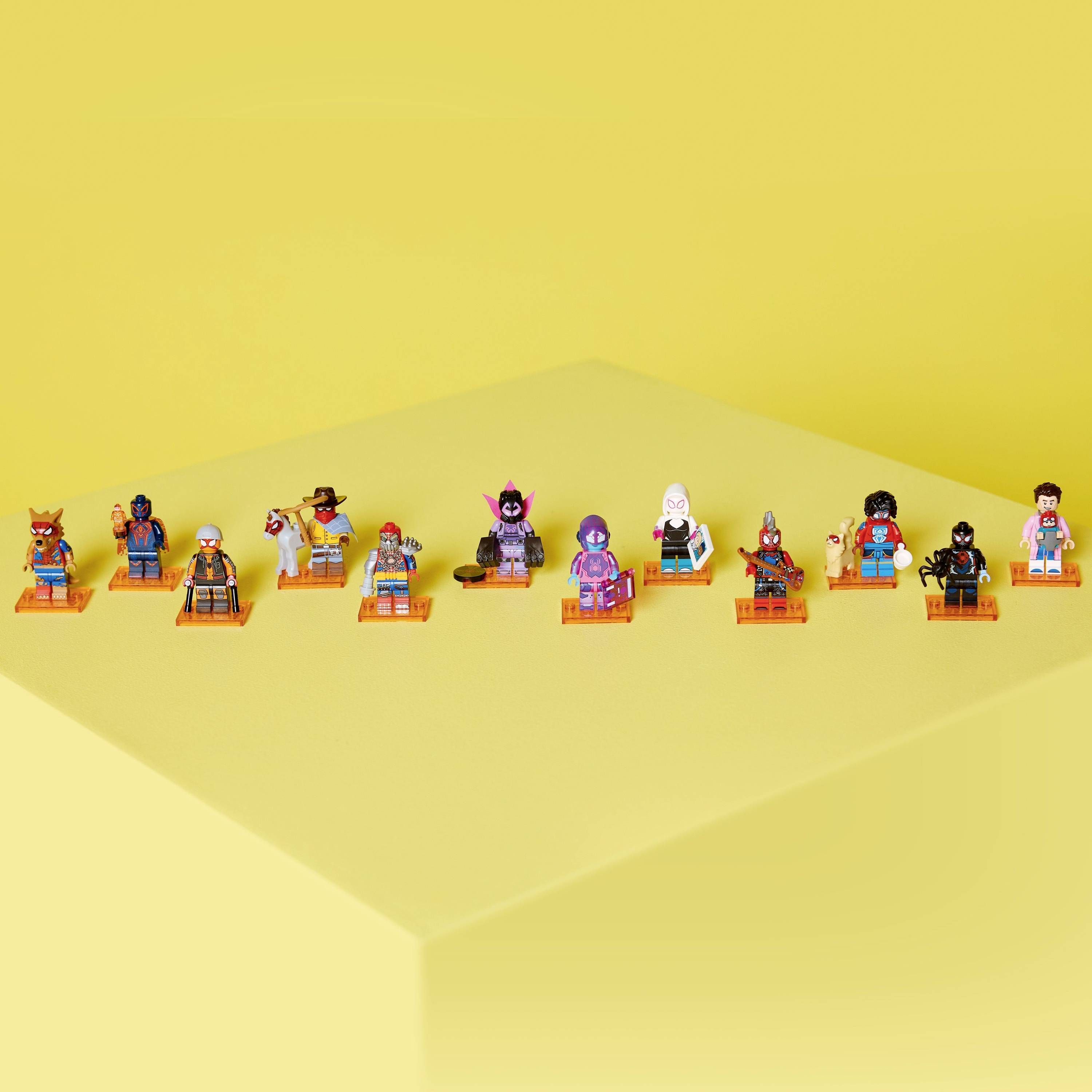 Dvanáct miniatur na oranžových podstavcích je uspořádáno v řadě před žlutým pozadím. Každá postava má jedinečné téma nebo oblečení.