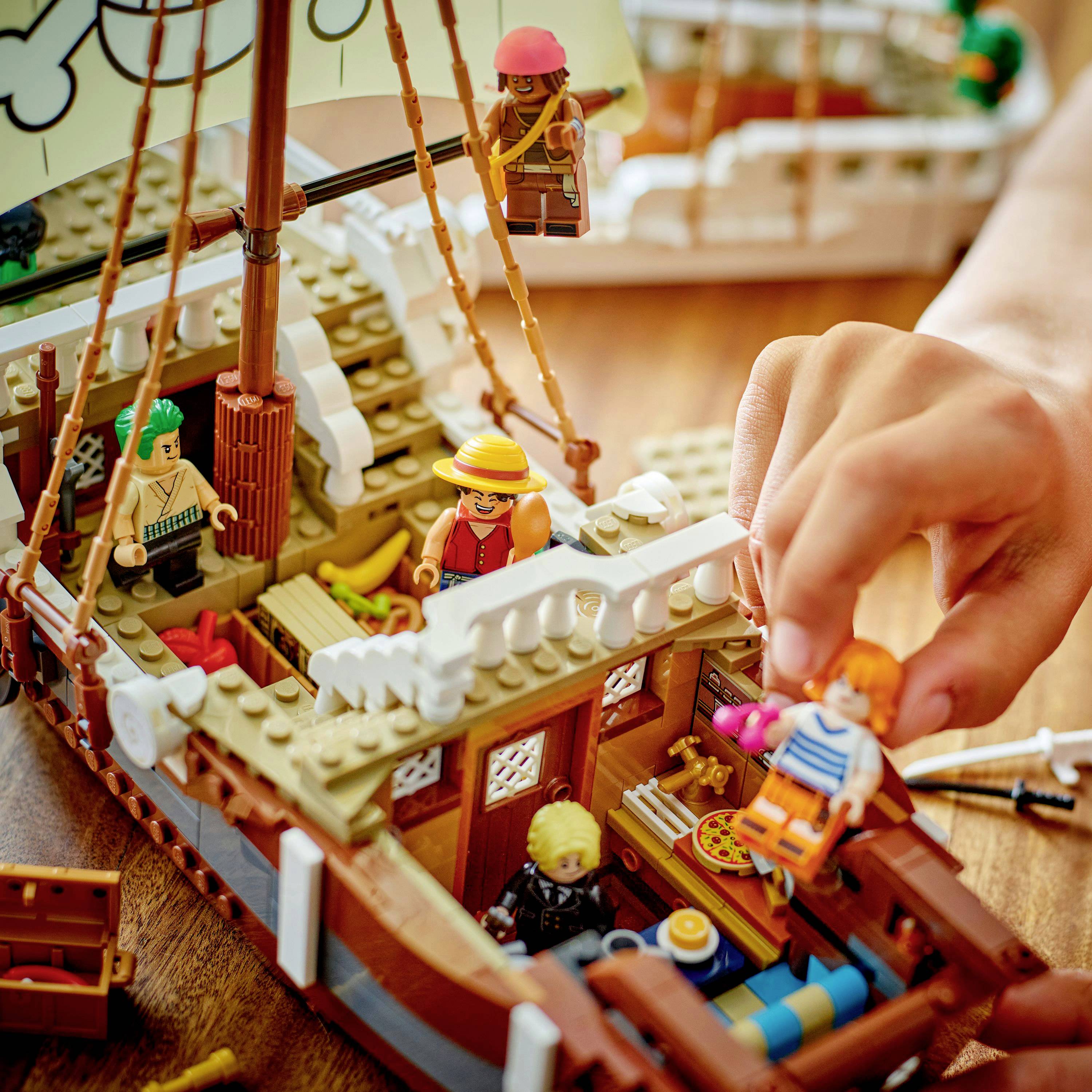 Děti si hrají s detailní sadou LEGO pirátské lodi, včetně miniaturních figurek a lodních doplňků, na dřevěném stole.