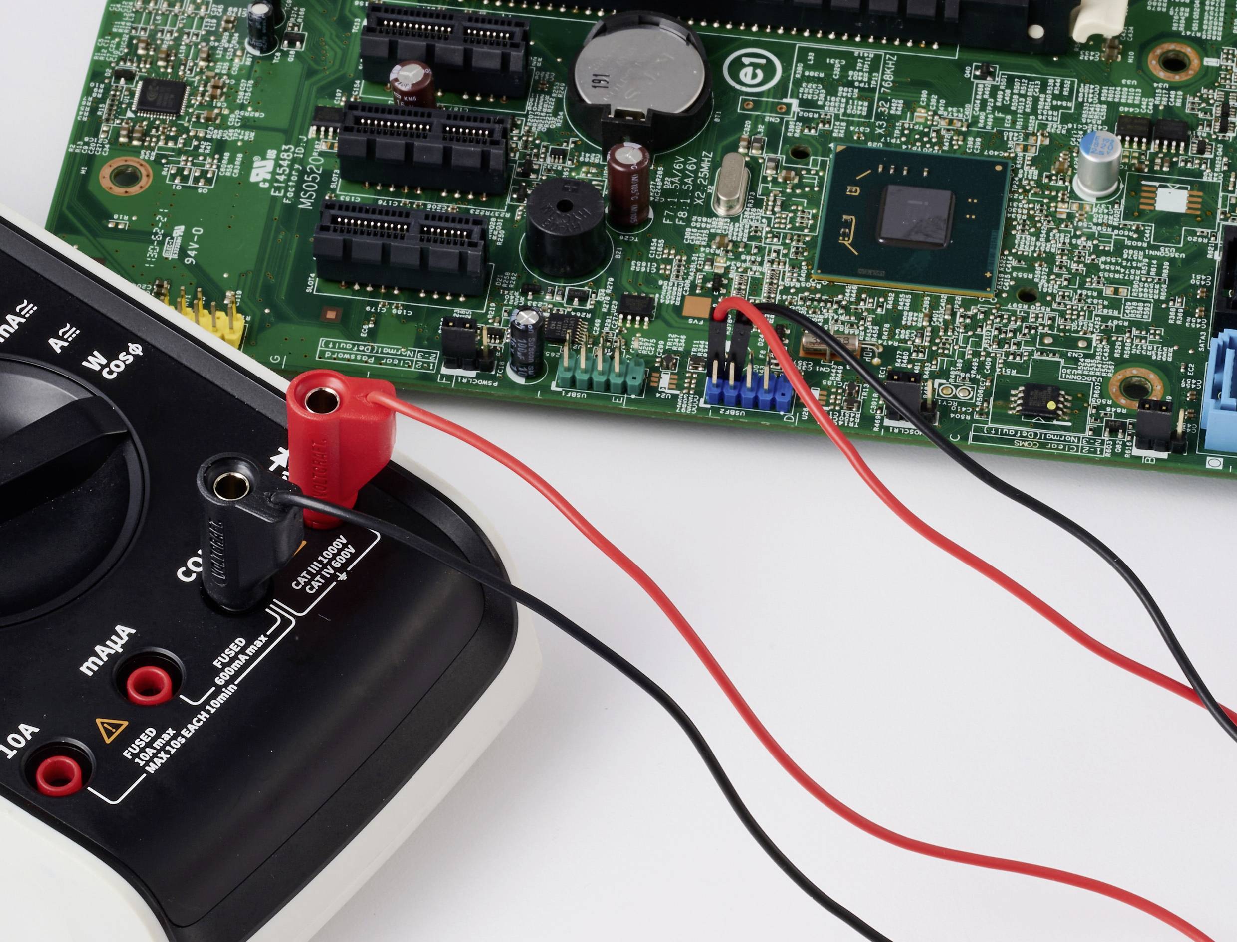 Multimetr připojený k desce plošných spojů, zobrazující zkušební uspořádání pro elektronické součástky a diagnostiku.