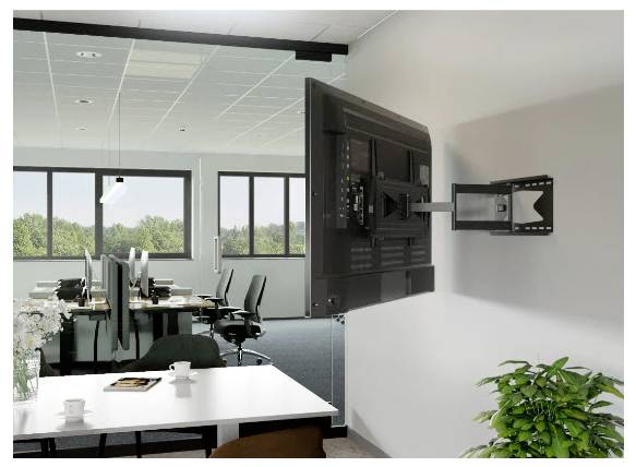 Kancelářský prostor s psacími stoly a židlemi, s nástěnnou televizí na nastavitelném rameni v popředí, vedle rostliny.