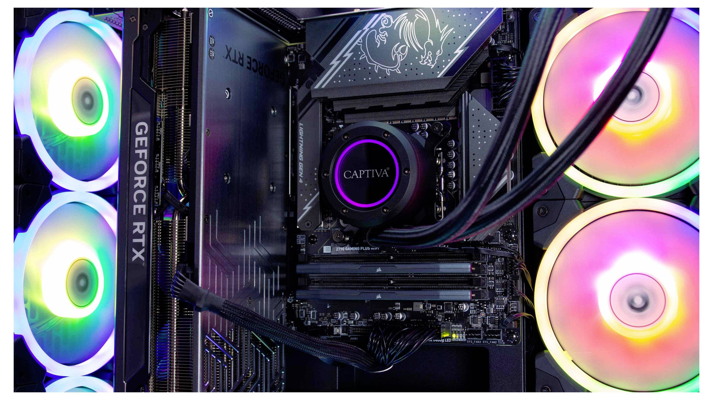 Vnitřek herního počítače s vícebarevnými LED ventilátory. Je zde vidět grafická karta GeForce RTX a komponenta značky 'CAPTIVA'.