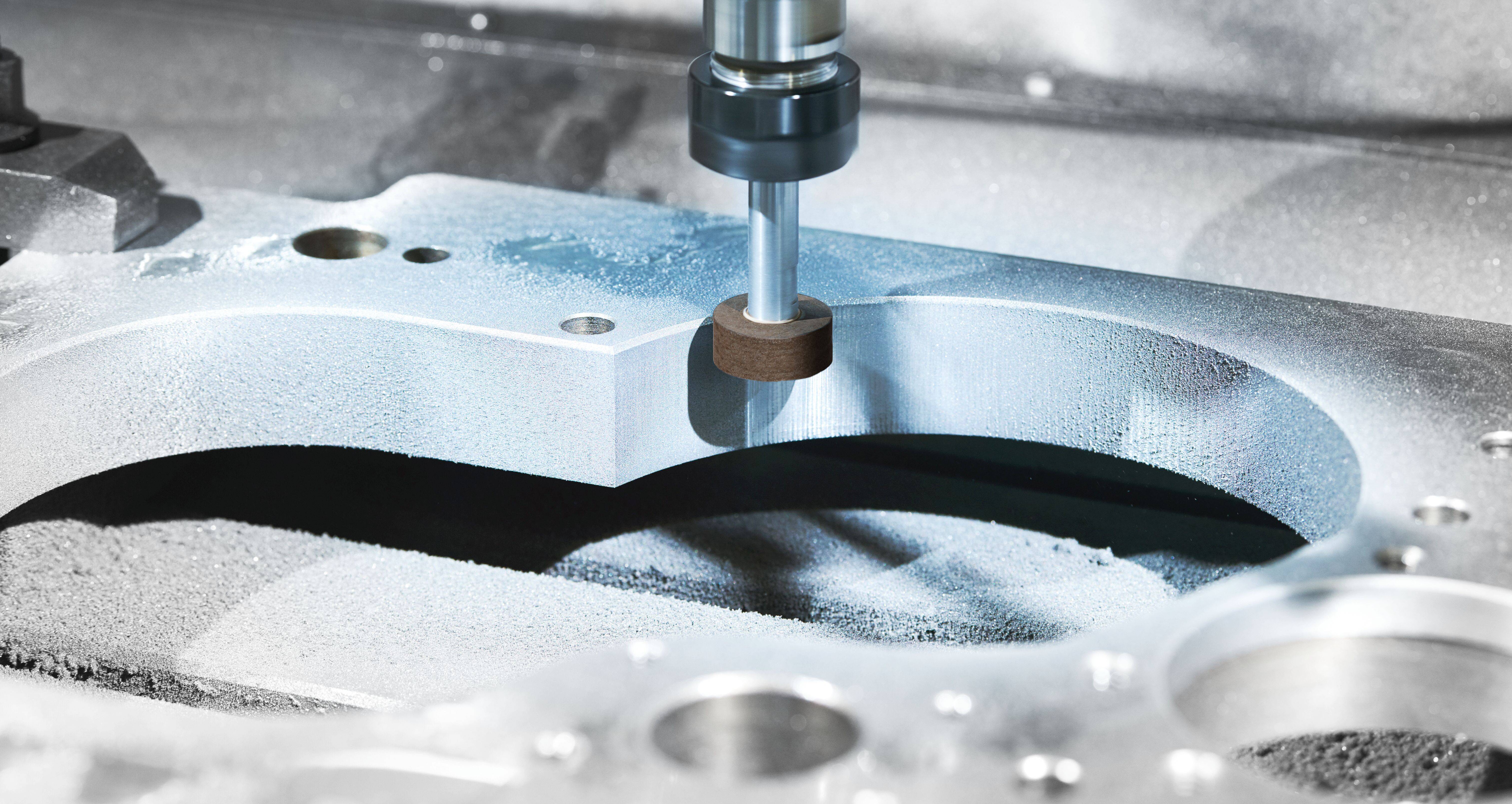 Detailní záběr CNC stroje, který obrábí kovovou součástku, zobrazující přesné řezání a hladkou strukturu povrchu s kovovými třískami kolem.