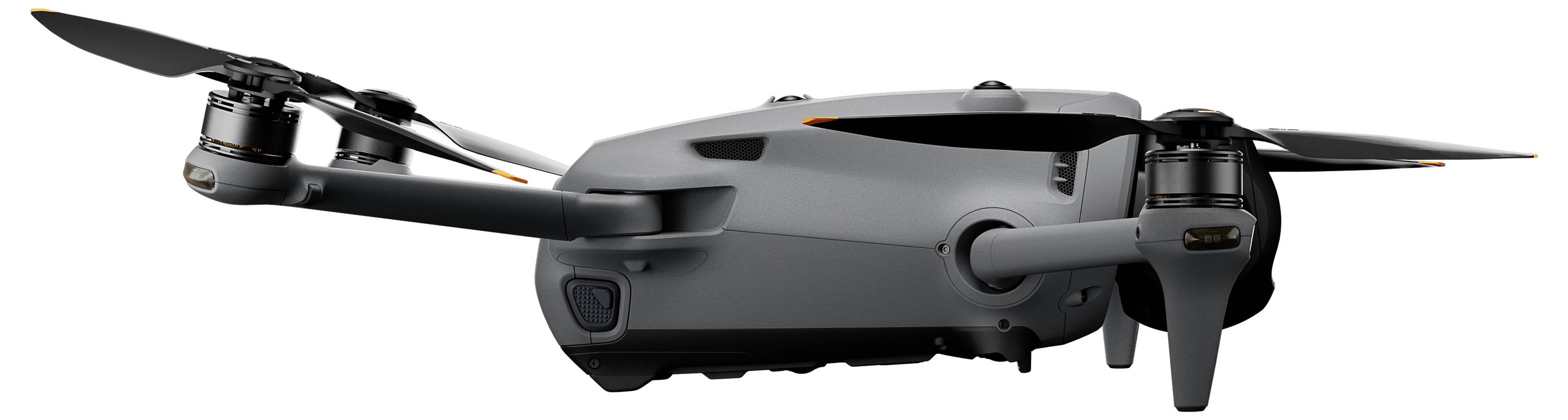 Kompaktní šedý dron se čtyřmi vrtulemi, pohled z boku. Dron vypadá elegantně a moderně, vhodný pro leteckou fotografii.