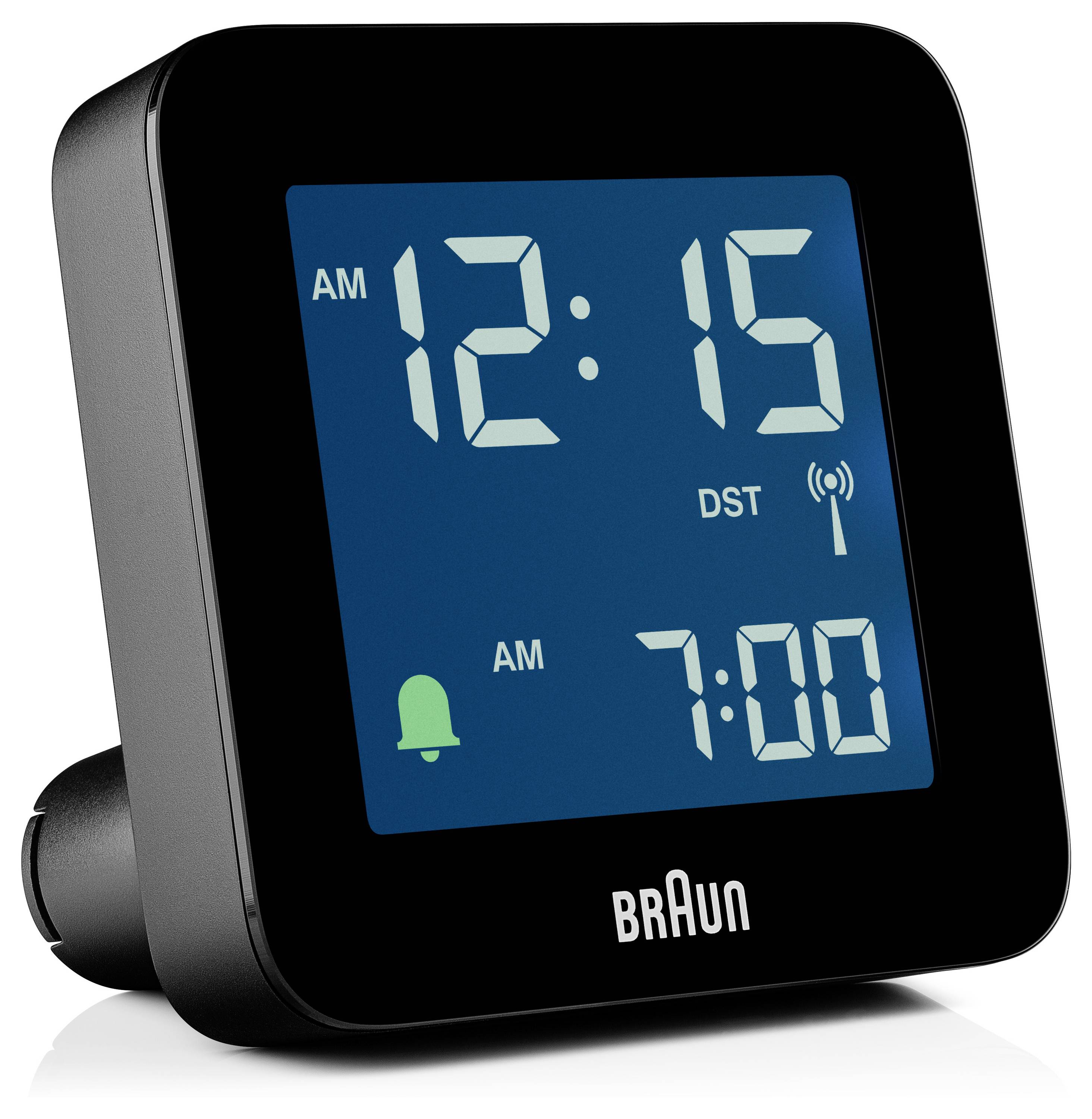 Digitální budík zobrazující '12:15 AM' s nastaveným budíkem na '7:00 AM'. Na displeji jsou viditelné aktivní indikátory budíku a letního času.