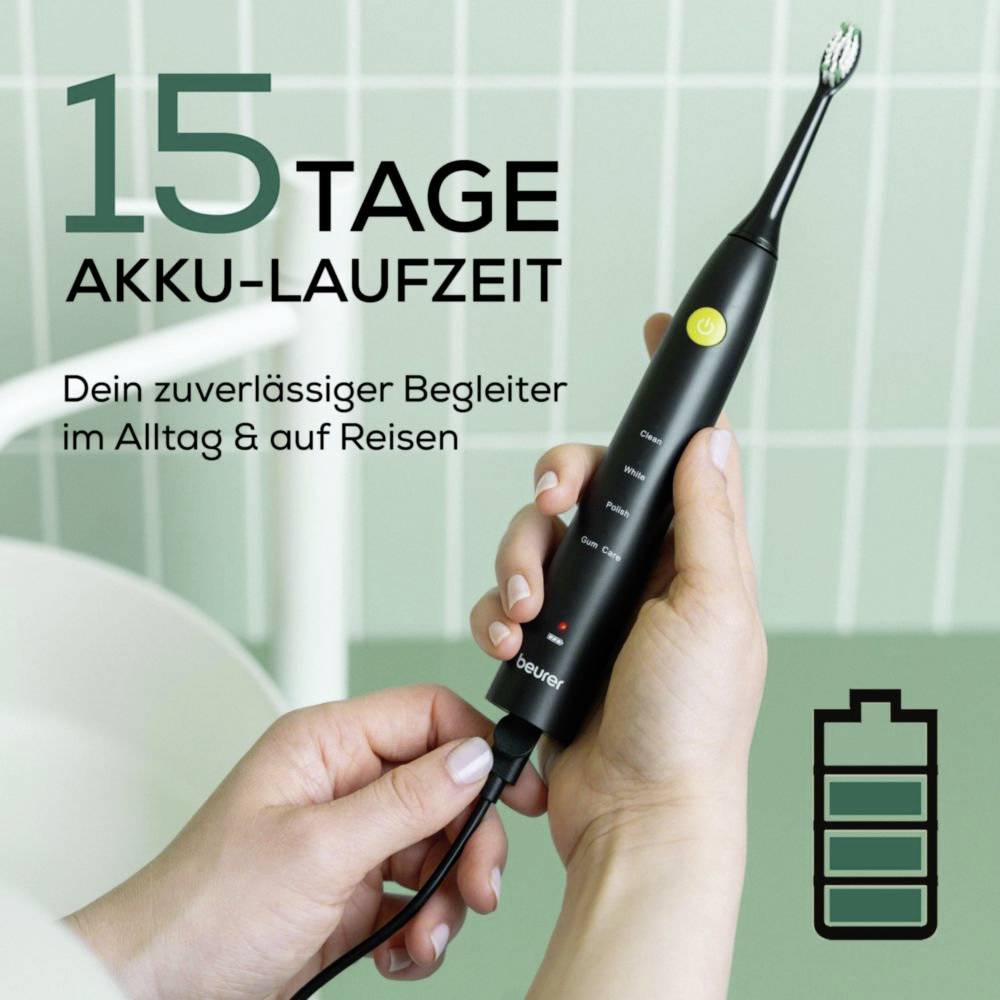 Ruka držící černý elektrický zubní kartáček s zeleným napájecím tlačítkem, vedle textu udávajícího 15denní výdrž baterie a ikony baterie.