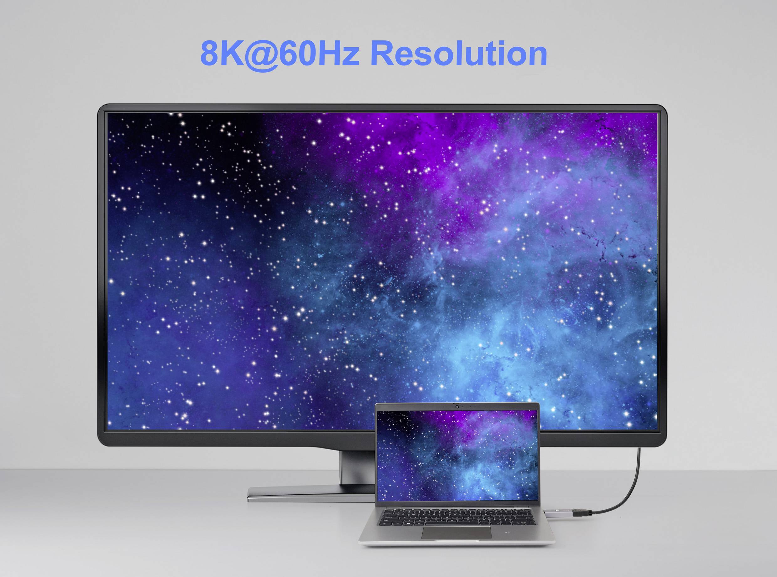 Velký monitor zobrazuje hvězdnatou modrofialovou galaxii s textem '8K@60Hz rozlišení'; připojený notebook zrcadlí stejný obraz.