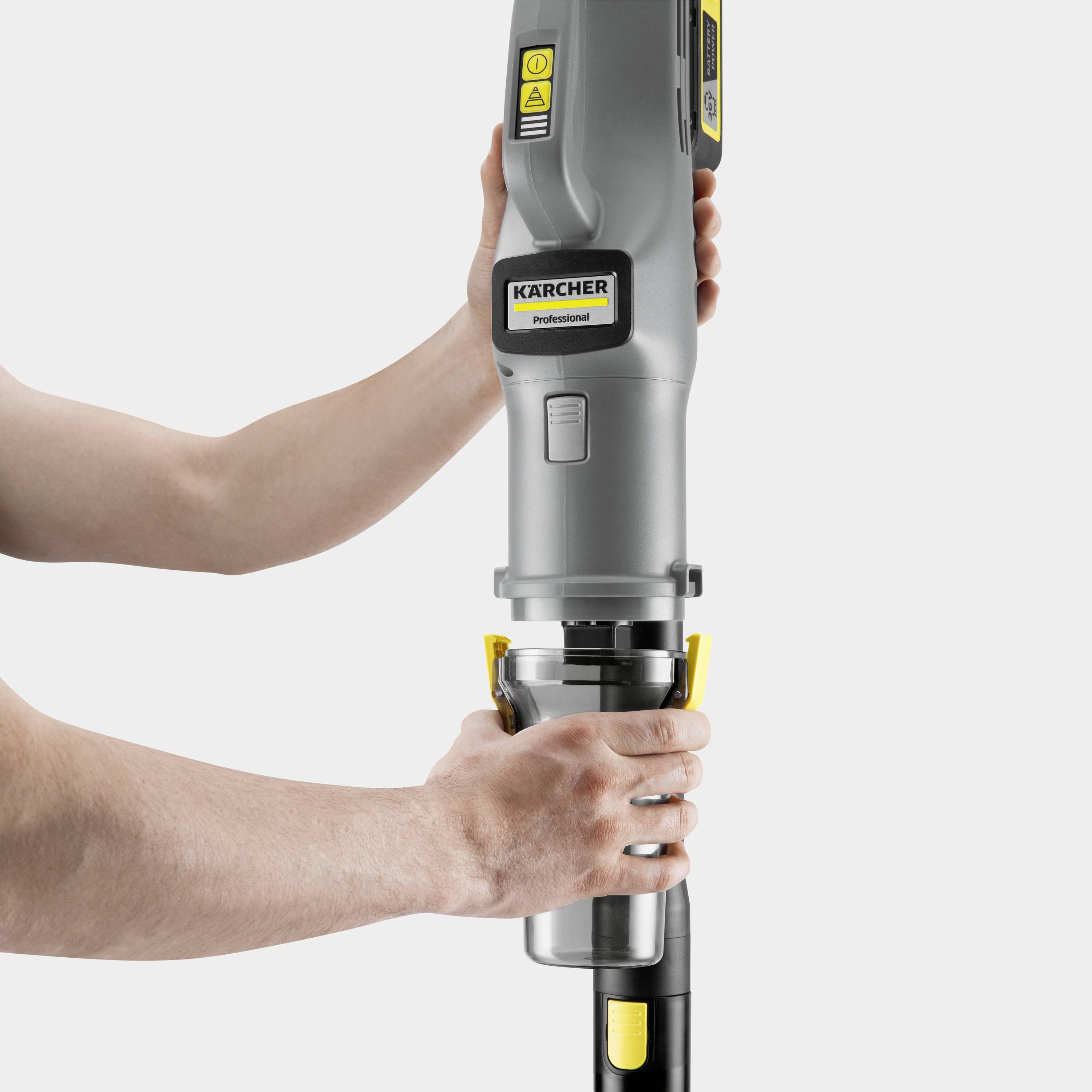 Osoba předvádí profesionální vysavač Kärcher s žlutým štítkem, přičemž poukazuje na jeho ergonomický design a úchop.