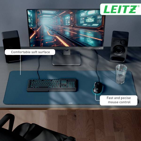 Sestava počítače 'LEITZ' s velkým monitorem zobrazujícím digitální scénu, klávesnicí, sklenicí a reproduktory na stole s modrou podložkou.