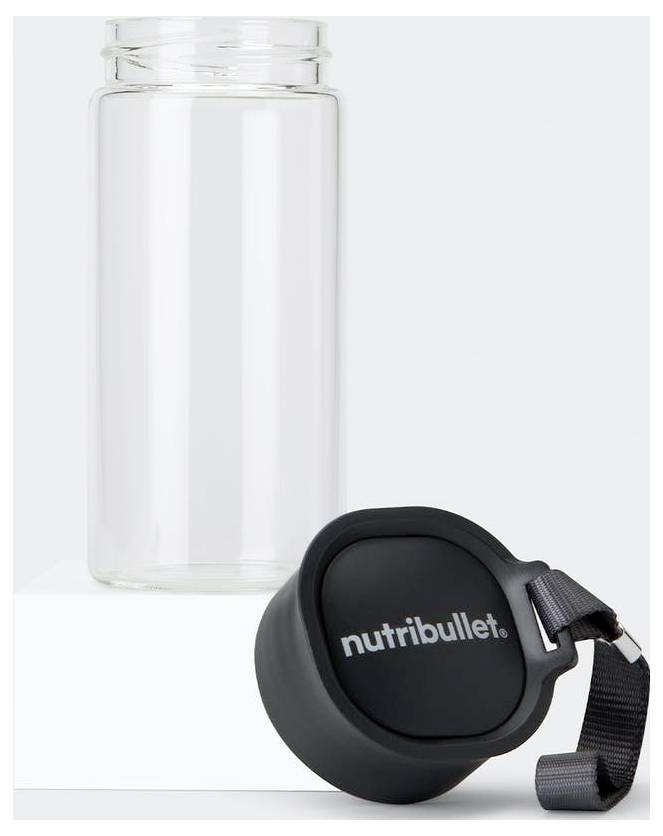Průhledná skleněná láhev NutriBullet s černým víčkem a nosným popruhem, umístěná na bílé platformě proti světle šedému pozadí.