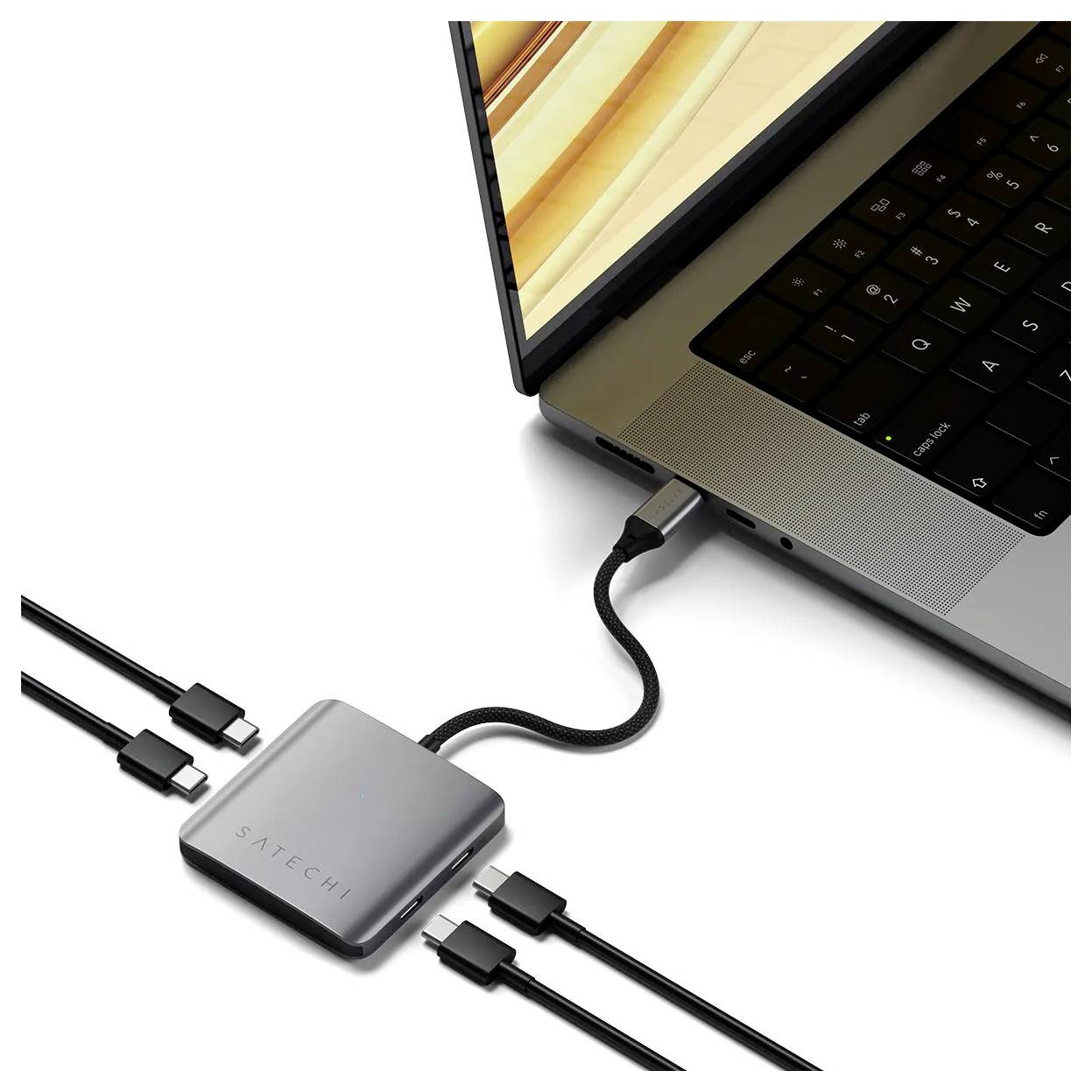 Laptop připojený k USB-C rozbočovači Satechi s několika kabely, což naznačuje rozšířené možnosti připojení.