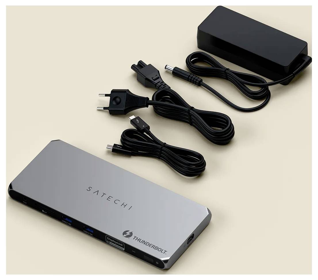 Dokovací stanice Satechi Thunderbolt s doprovodným napájecím adaptérem a kabely je umístěna na béžovém povrchu.