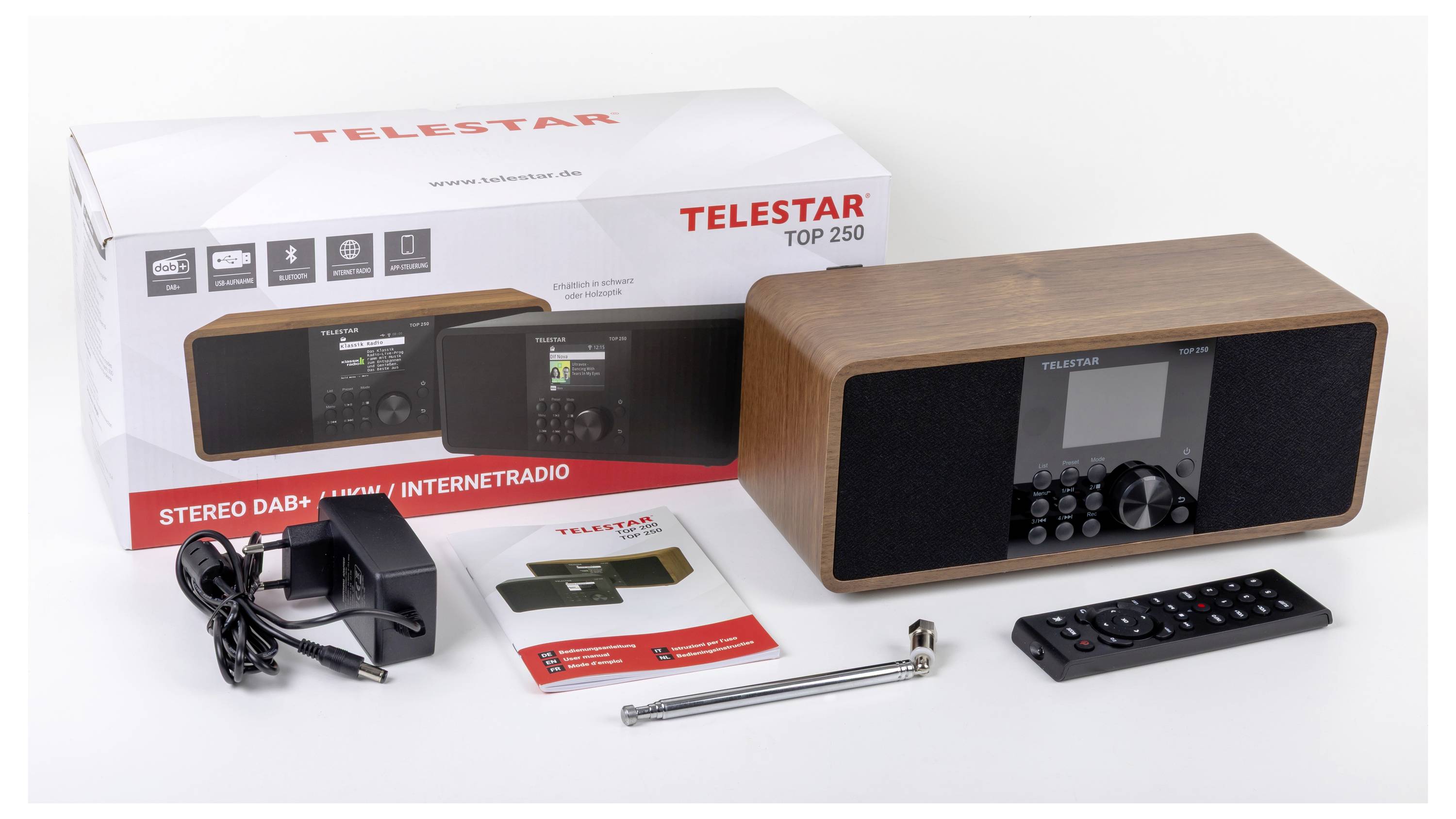 Krabice a obsah Telestar Top 250 stereo. Zahrnuje DAB+ rádio s dřevěným povrchem, napájecí adaptér, dálkový ovladač, manuál a anténu.