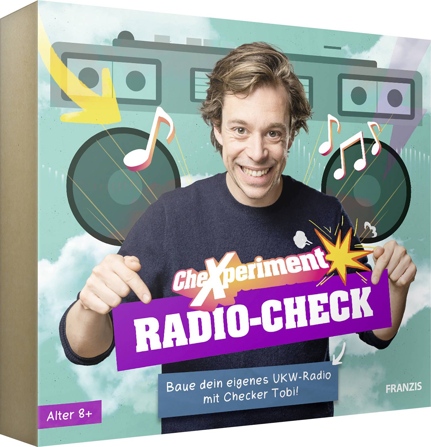 Osoba se usmívá a ukazuje na barevnou krabici označenou 'Experiment Radio-Check', která naznačuje domácí stavebnici rádia vhodnou pro děti od 8 let.