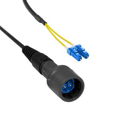 Optický kabel s černým konektorem a dvěma modrými LC konektory připojenými k žlutým vodičům, používaný pro přenos dat.