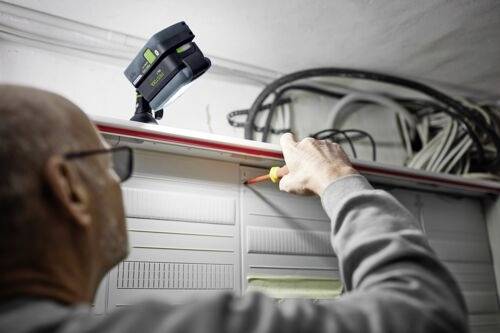 Osoba používá šroubovák při práci s elektrickým vedením uvnitř rozvodné skříně, přičemž přenosné pracovní světlo osvětluje prostor.