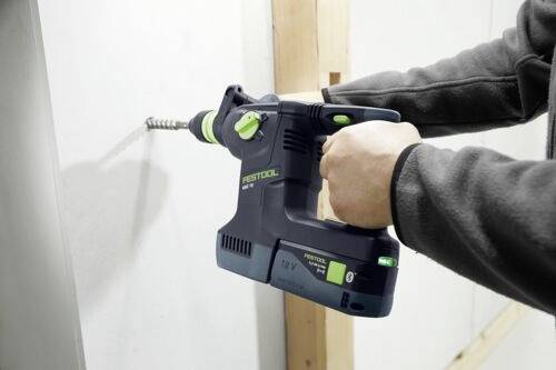 Osoba používá bezdrátovou vrtačku k vyvrtání díry do bílé stěny a zaměřuje se na ergonomický design její rukojeti.