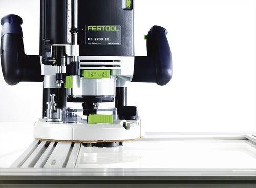 Ruční frézka Festool OF 2200 EB umístěná na rovném povrchu, která ukazuje svou robustní konstrukci a přesné komponenty určené pro profesionální truhlářství.