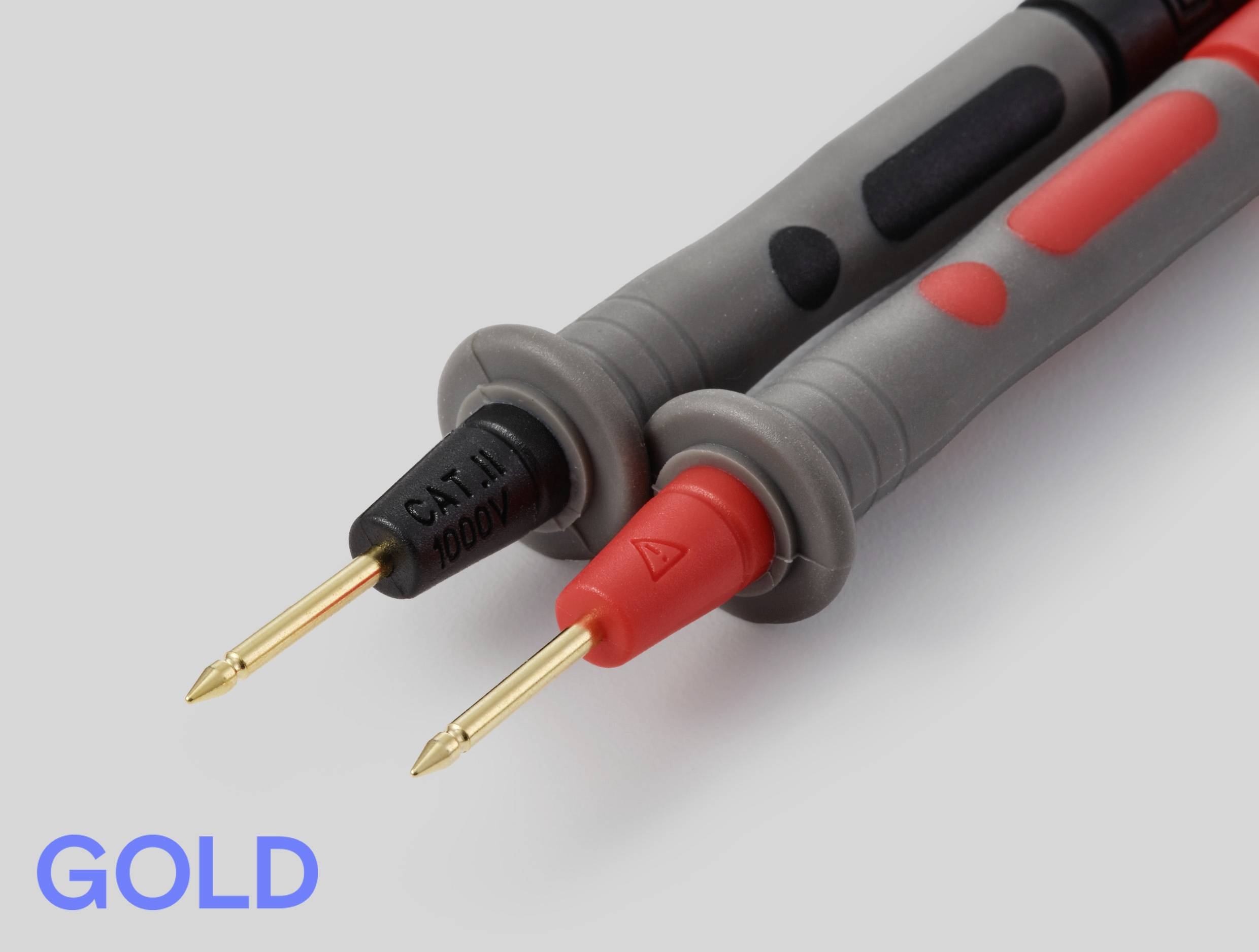Dva elektronické testovací vodiče z bezprostřední blízkosti, jeden černý a jeden červený, s pozlacenými hroty. Text „GOLD" je tučně zobrazen modře v levém dolním rohu.