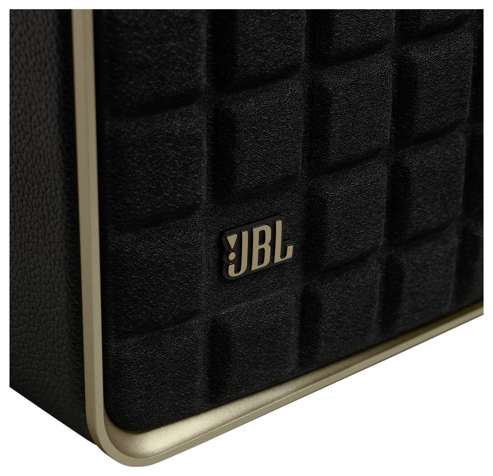 Detailní záběr reproduktoru JBL s černým texturovaným povrchem a zlatým lemováním, na kterém je výrazně zobrazen logotyp JBL.