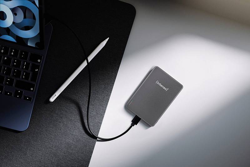 Laptop připojený k externímu pevnému disku na stole, s tabletem poblíž, což naznačuje technologické pracovní prostředí.