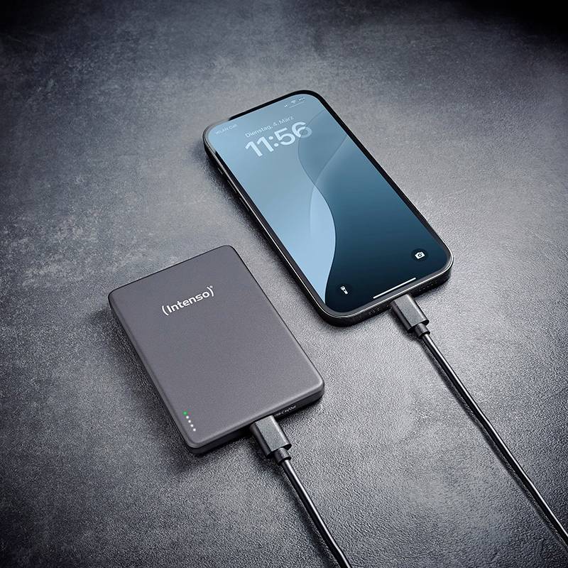 Chytrý telefon je připojen k externímu powerbance pomocí kabelu, což ukazuje nabíjecí situaci na tmavém povrchu.