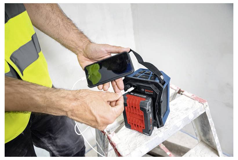 Osoba v reflexní vestě připojuje smartphone k přenosné zásuvkové liště umístěné na štaflích.