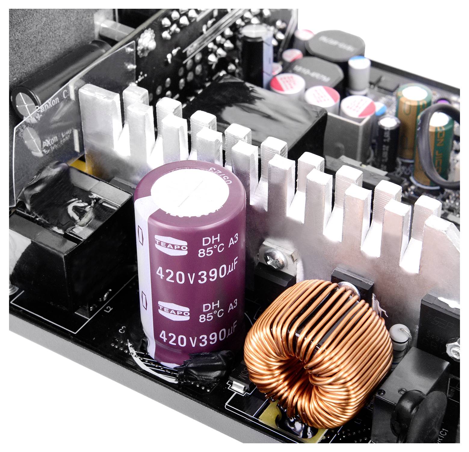 Detailní pohled na napájecí desku počítačového zdroje zobrazující velký kondenzátor označený '420V 390μF', chladič a měděnou cívku.