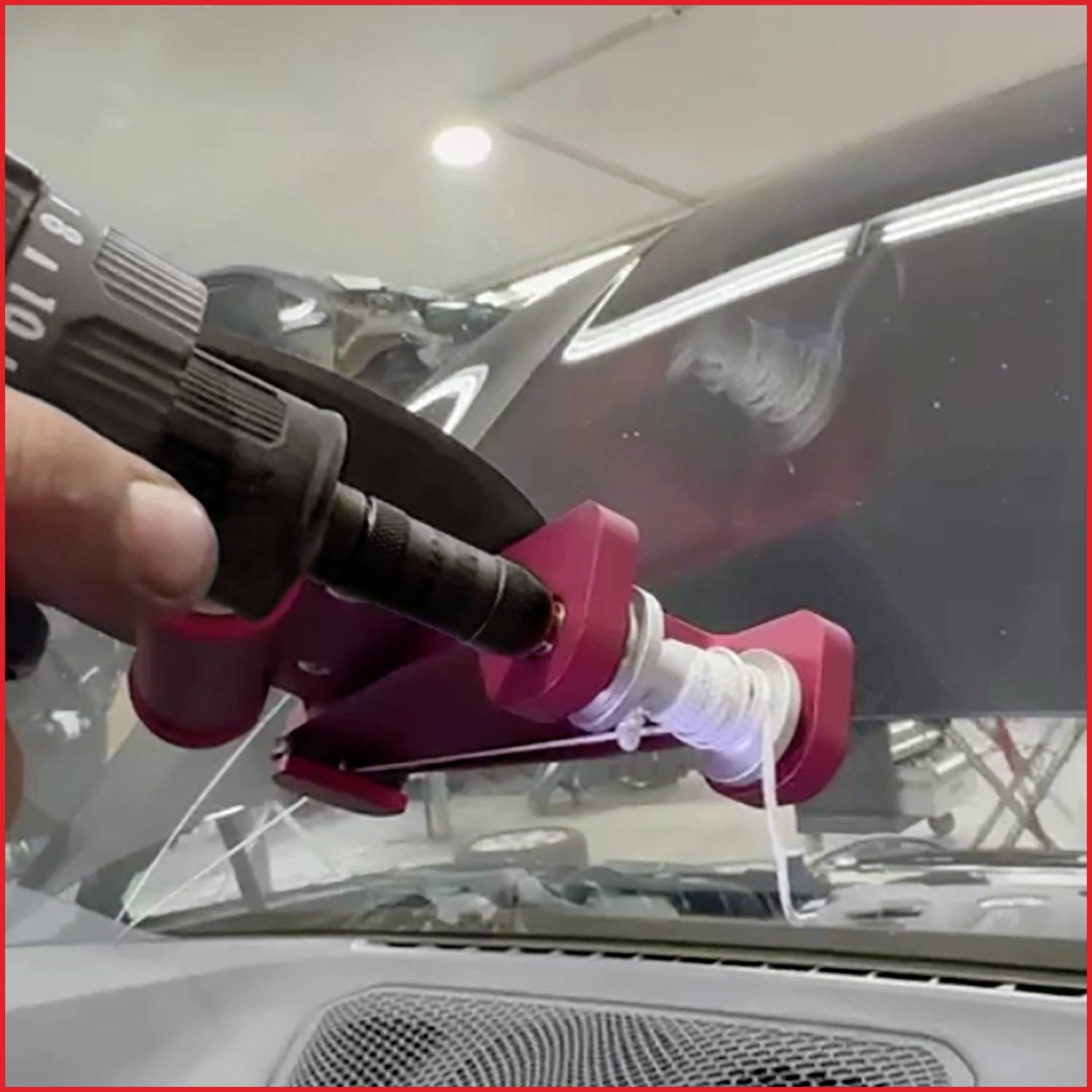 Ruka používá nástroj k opravě trhliny ve skle automobilového čelního skla, což naznačuje probíhající proces opravy čelního skla uvnitř místnosti.