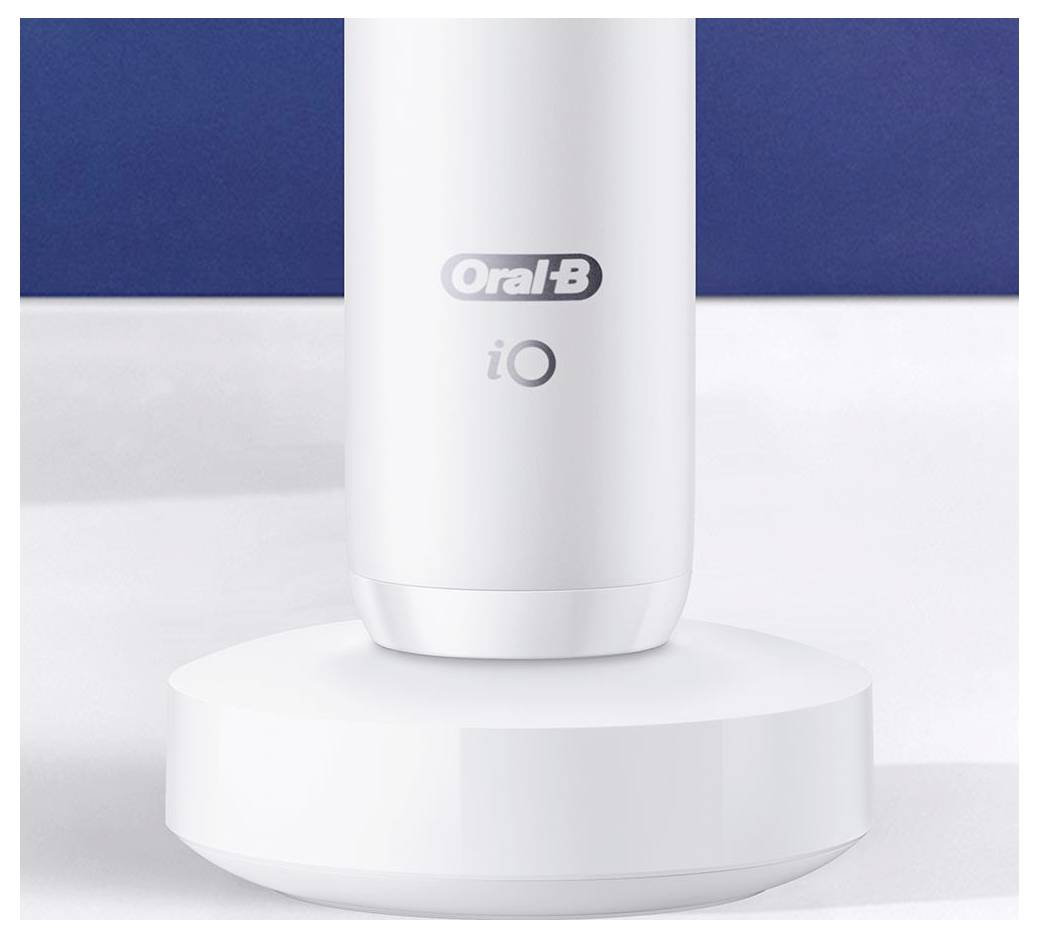 Bílá elektrická základna zubního kartáčku s logem „Oral-B iO", umístěná na bílém povrchu s modrým pozadím.