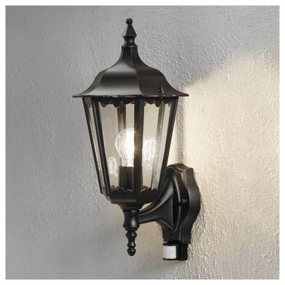 Černá, vintage lampa připevněná na zdi, uvnitř s žhnoucí žárovkou, osvětlující okolní texturovaný povrch.