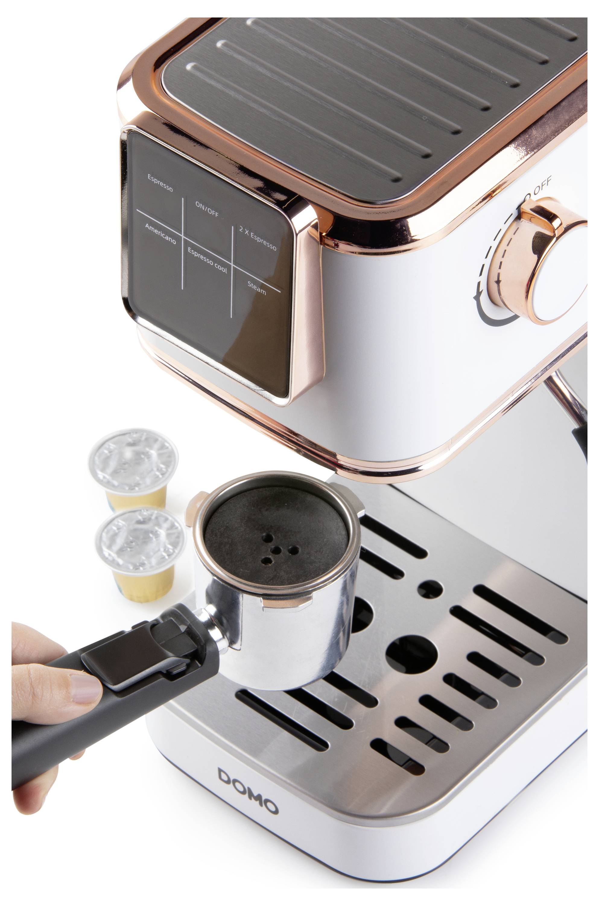Osoba vkládá portafiltr naplněný mletou kávou do elegantního, moderního kávovaru na espresso. Poblíž jsou dvě kapsle.