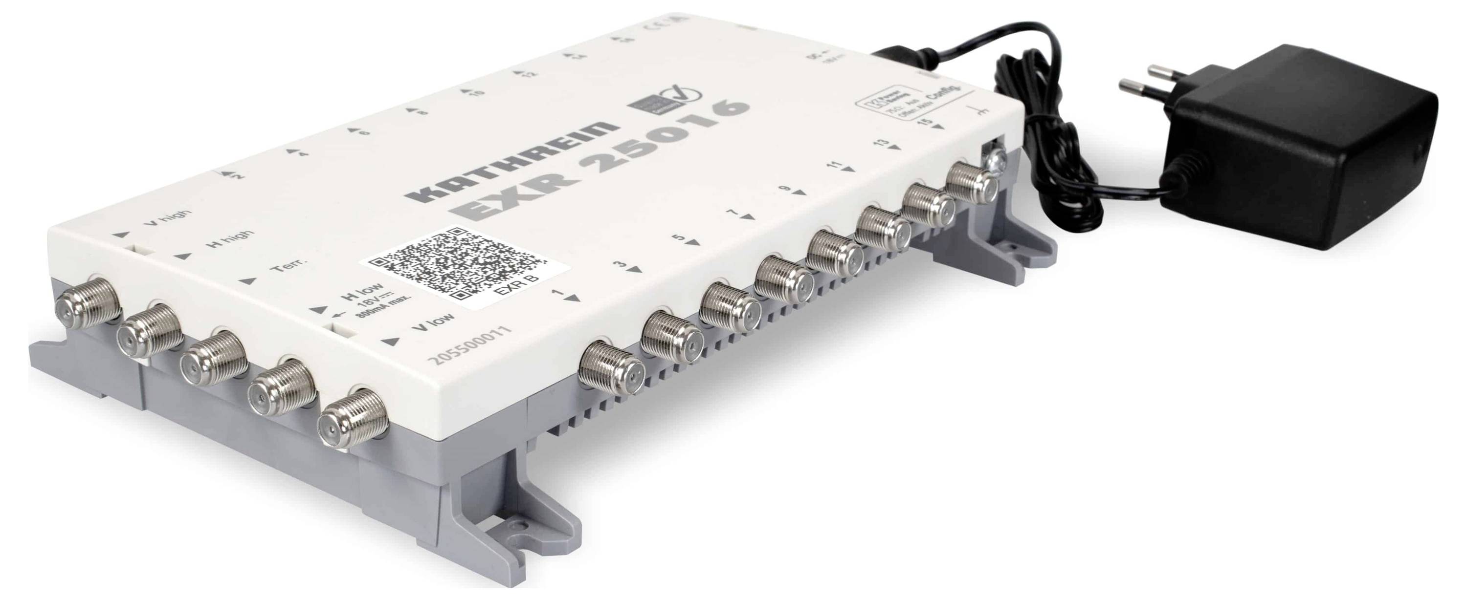 Bílé elektronické zařízení označené štítkem 'KATHREIN EXR 25016' s několika koaxiálními konektory na straně; součástí je napájecí adaptér.