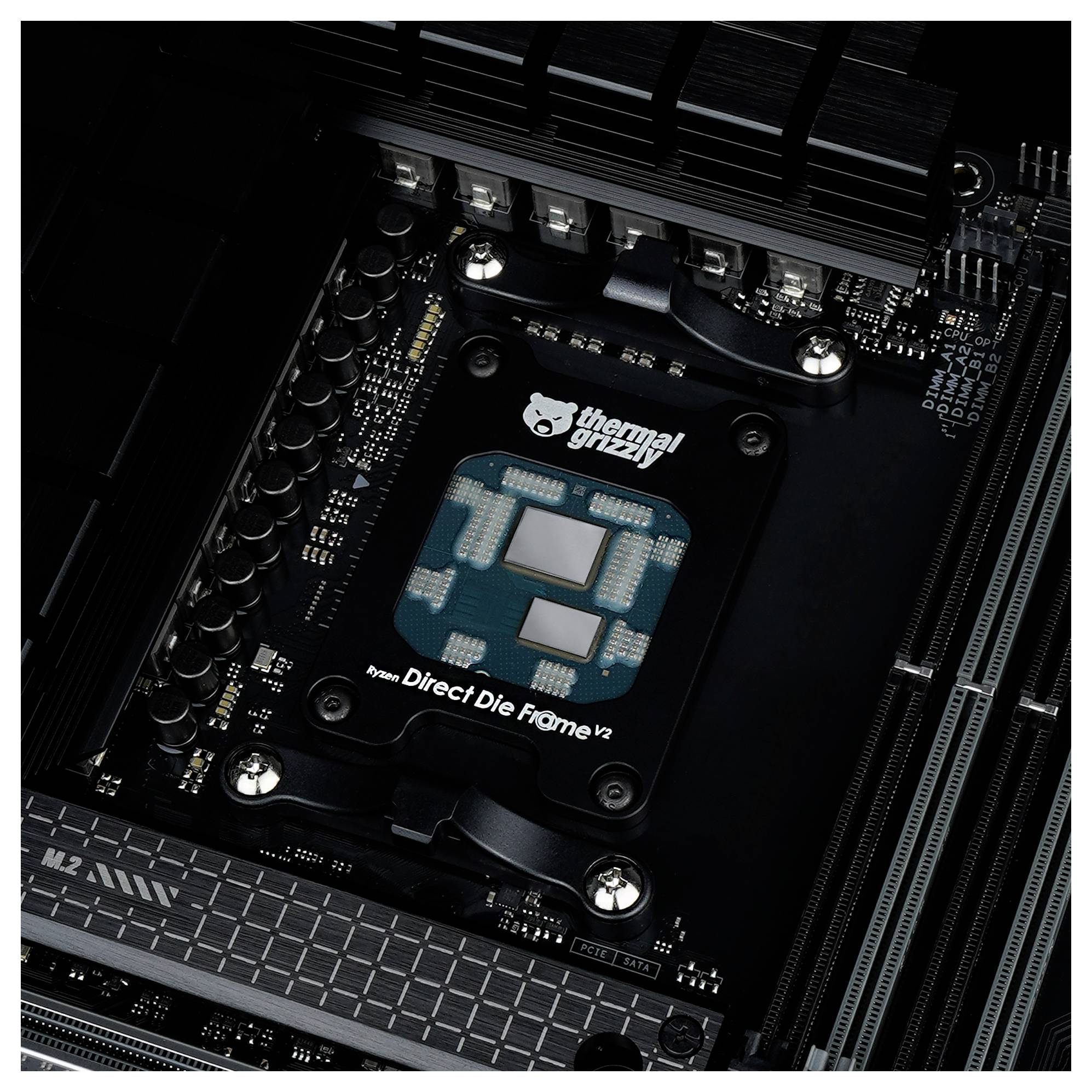Počítačová základní deska s nainstalovaným rámečkem Thermal Grizzly Direct Die Frame V2, obklopená kondenzátory a chladiči.
