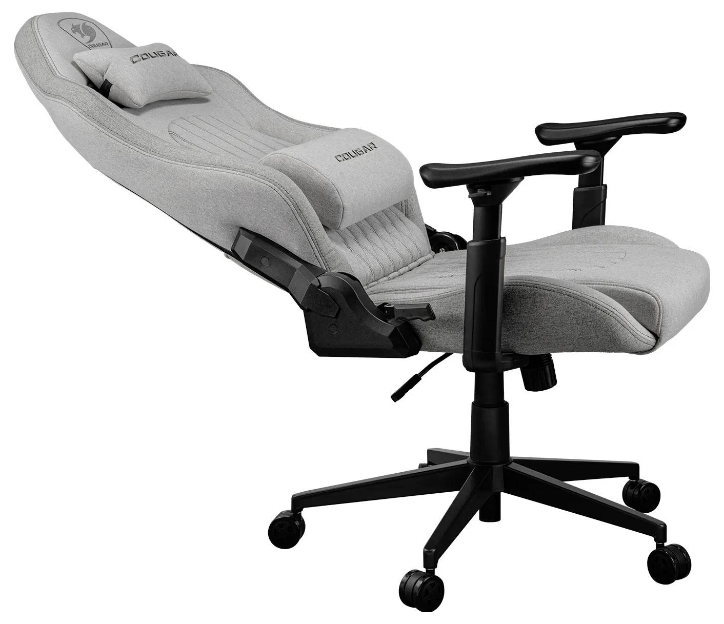 Šedá ergonomická herní židle s nastavitelnými opěrkami rukou a vysokým opěradlem, vybavená odnímatelným polštářem na hlavovou opěrku, umístěná na černé základně s kolečky.