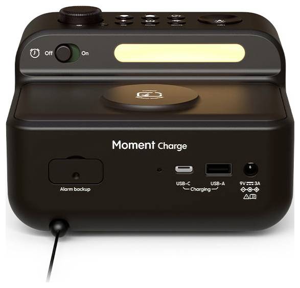 Černé elektronické zařízení označené štítkem 'Moment Charge' s porty USB-C a USB-A, funkcí záložního alarmu a vypínačem na horní straně.