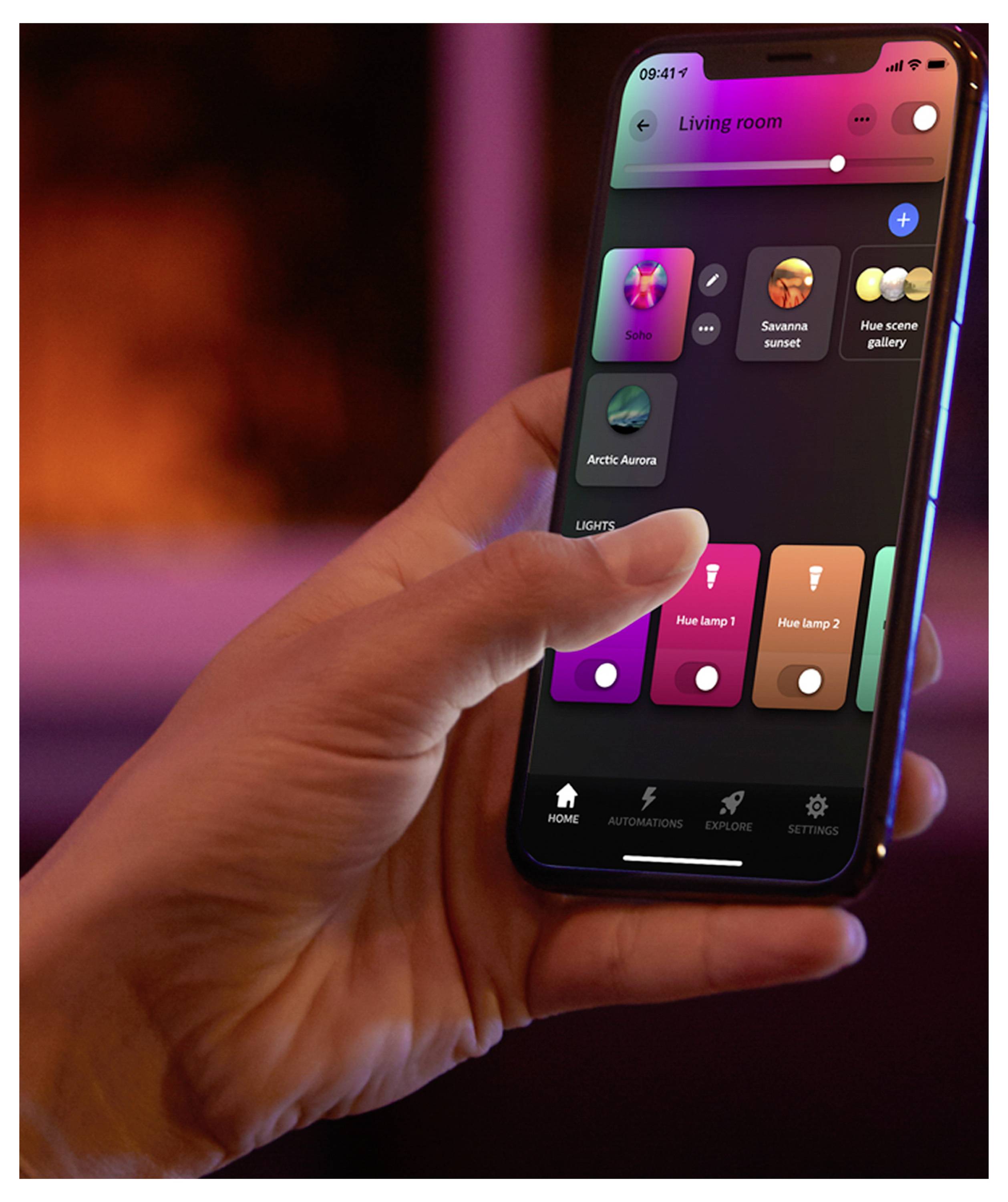 Ruka ovládá smartphone se zobrazenou aplikací pro chytré ovládání osvětlení, která ukazuje různá světelná nastavení pro obývací pokoj.
