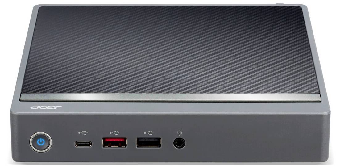 Malá šedá počítačová skříň s USB a audio porty na přední straně. Má strukturovaný horní povrch a vypínač umístěný vlevo vpředu.