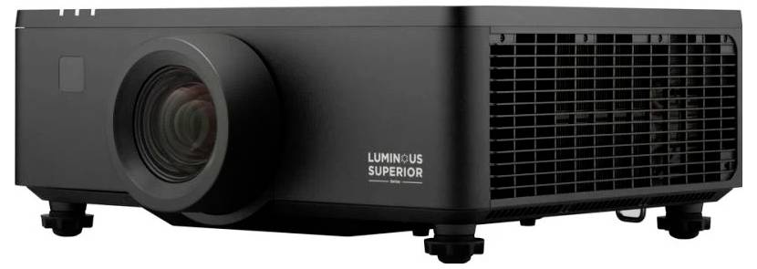 Černý projektor označený nápisem "Luminous Superior" s velkým objektivem a větracími otvory na straně, umístěný na rovném povrchu.